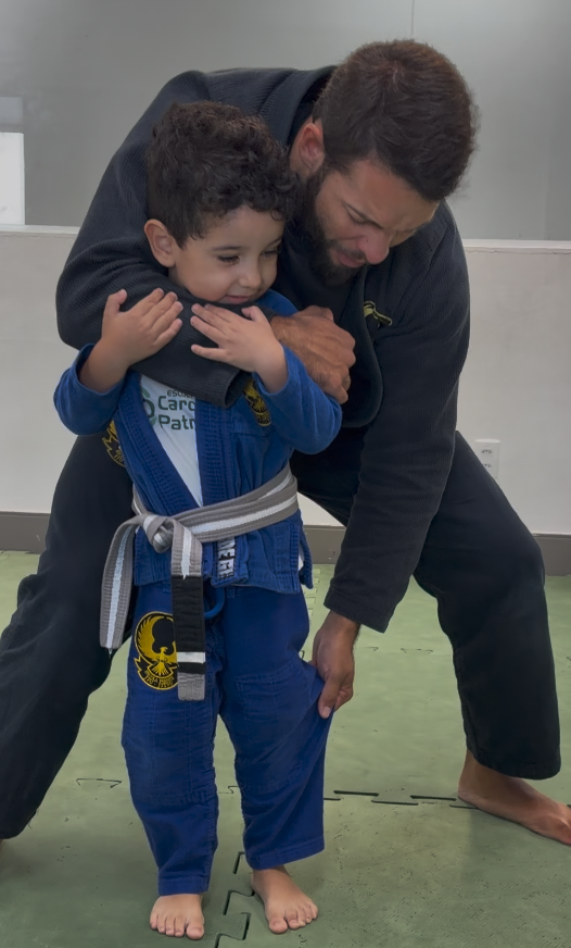 Turma de crianças rindo em roda durante o aquecimento da aula de Jiu-Jitsu