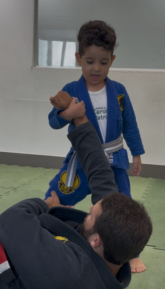 Professor da Phenix sorrindo com um grupo de crianças em kimono na aula